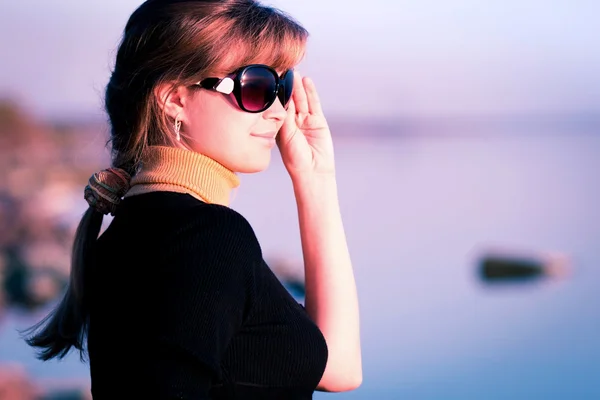 Portret van een mooi meisje in zonnebril op de rivier bank — Stockfoto