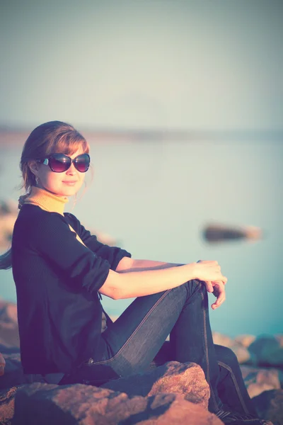Vintage foto på flickan sitter på klipporna vid floden — Stockfoto