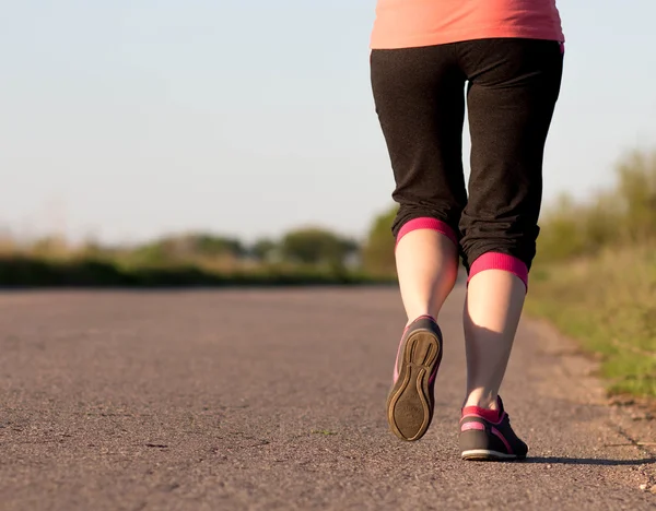 Chica corre a lo largo del camino de asfalto — Foto de Stock