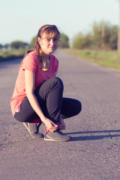 Ragazza allacciatura lacci delle scarpe facendo sport — Foto Stock