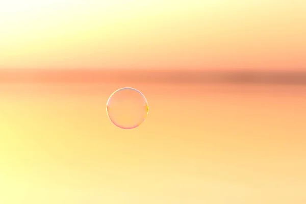 Мыльный пузырь летит над водой на закате — стоковое фото