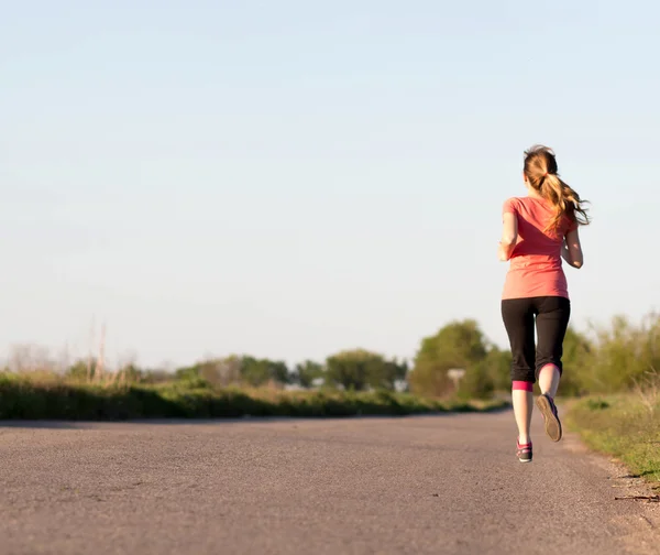 Ragazza corre lungo la strada asfaltata — Foto Stock