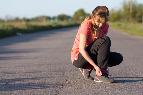 Ragazza che lega i lacci delle scarpe facendo jogging — Foto Stock