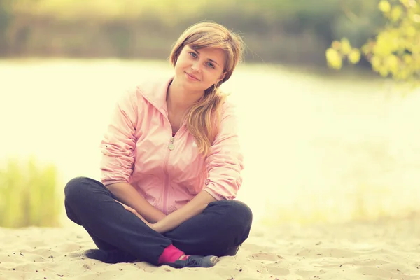 美丽的姑娘坐在沙滩上 — 图库照片