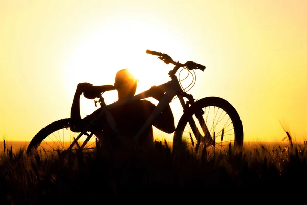 Um jovem em um campo segurando uma bicicleta — Fotografia de Stock