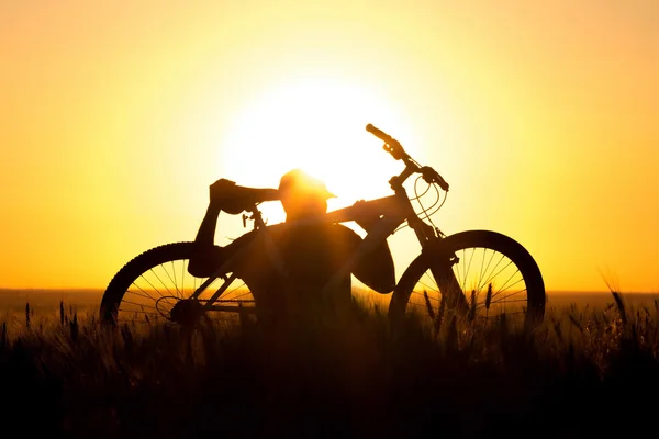 Um jovem em um campo segurando uma bicicleta — Fotografia de Stock