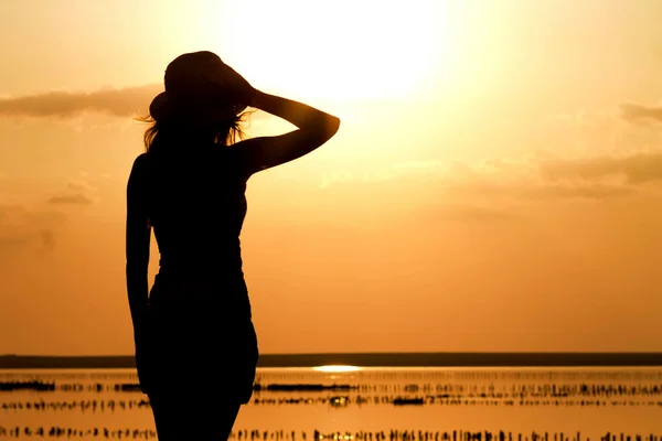 Silhouette di una giovane ragazza sul mare con un cappello — Foto Stock