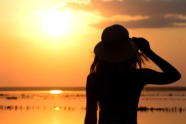 Silhouette of a young girl on the sea in a hat — Stock Photo, Image