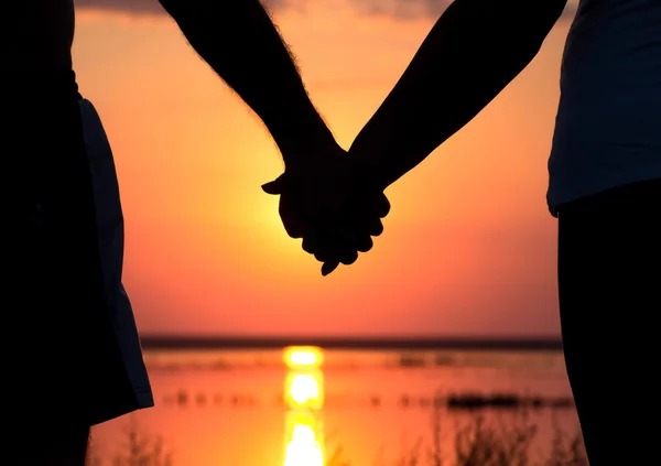 Paar bij zonsondergang hand in hand — Stockfoto