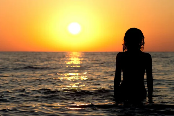 Silhouette di una ragazza in costume da bagno in mare all'alba — Foto Stock