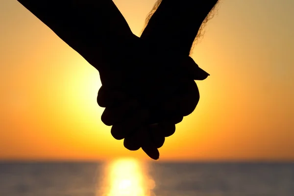 Silhouet van het paar bij zonsondergang hand in hand — Stockfoto