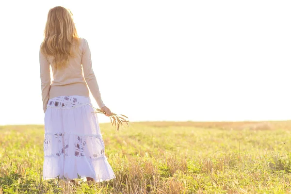 Chica joven caminando en un campo con orejas en la mano — Foto de Stock