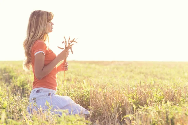 Молодая красивая девушка в поле с ушами в руке — стоковое фото