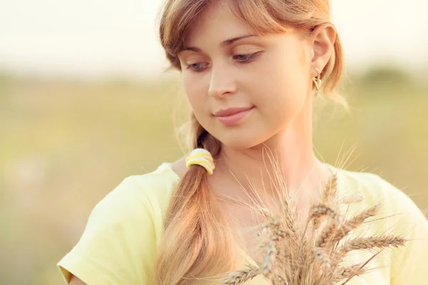 Jovem menina bonita no campo com orelhas na mão — Fotografia de Stock
