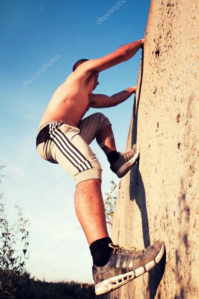 sports guy climbs on a concrete wall