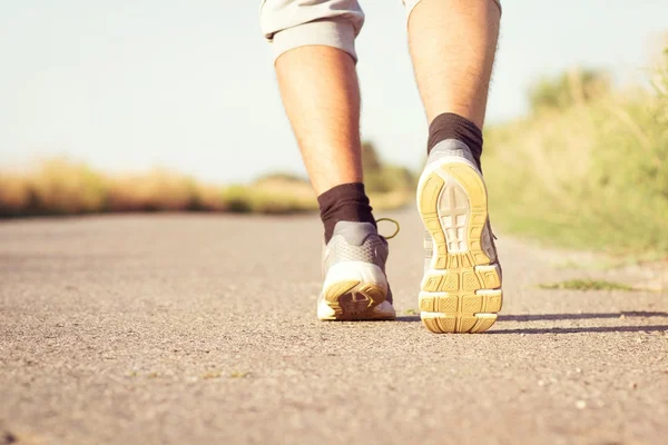 Чоловік біжить ногами на асфальтованій дорозі — стокове фото