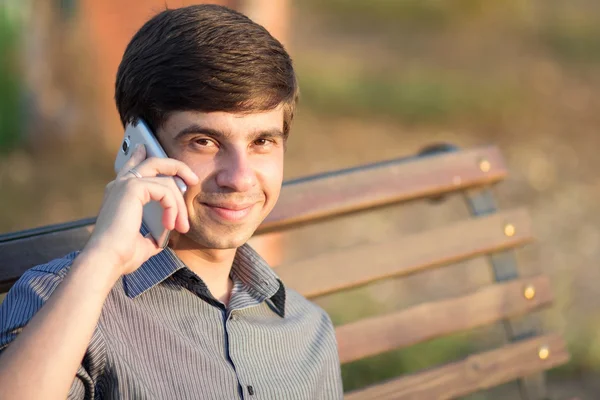 Tezgah üzerinde bir akıllı telefon ile genç adam — Stok fotoğraf