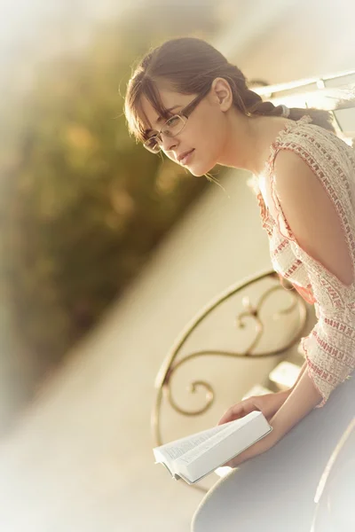 Mladá dívka čtení Bible na lavičce v parku — Stock fotografie