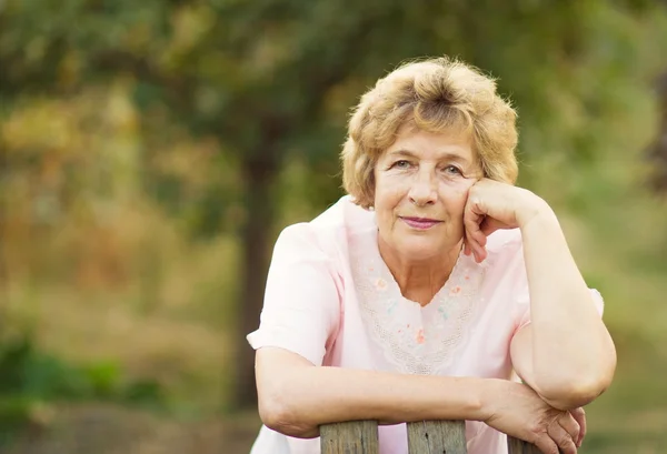 Oudere vrouw in de buurt van een wicket naar de tuin — Stockfoto