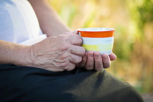 Oudere vrouw met een kop van drank — Stockfoto