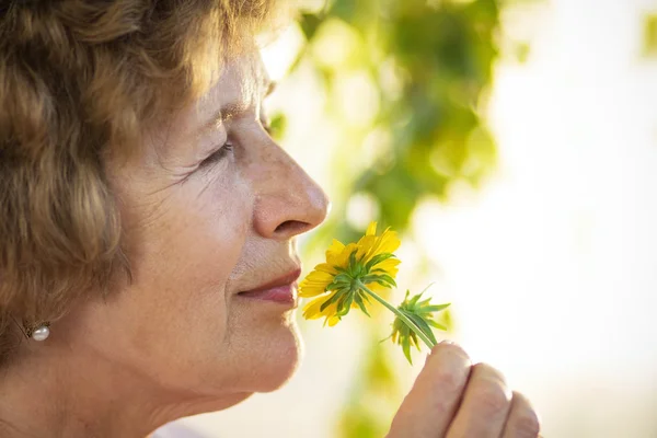 Oma ruikt een gele bloem — Stockfoto