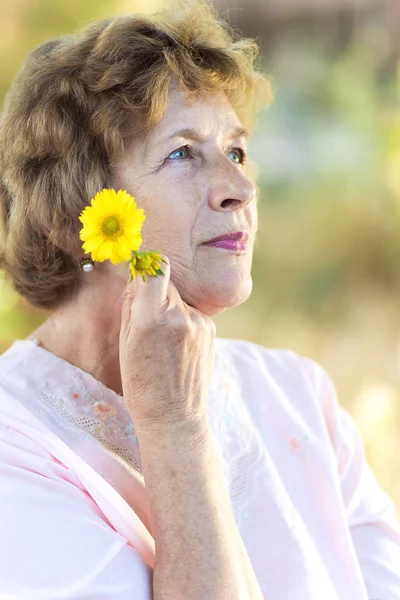 Gelukkig oudere vrouw met bloemen — Stockfoto