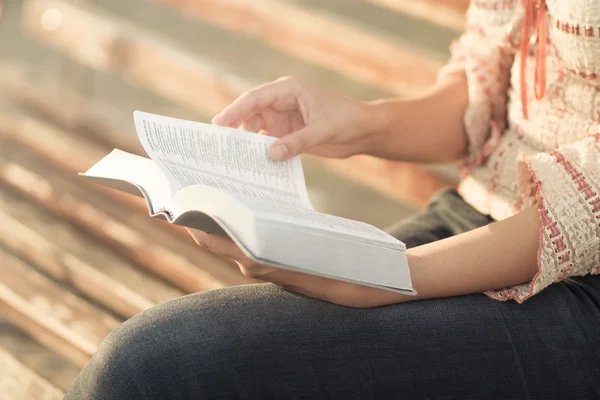 Mujer leyendo un libro sentado en el banco — Foto de Stock