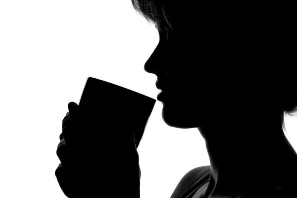 Silhuetten av en kvinna med en kopp i händer — Stockfoto