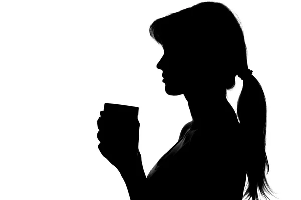 Silueta de una mujer con una taza en las manos — Foto de Stock