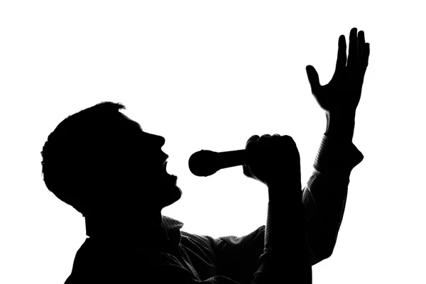 A young man singing into a microphone raising his hands — Stock Photo, Image