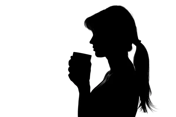 Silueta de una mujer con una taza en las manos — Foto de Stock