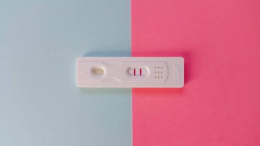 HCG testi mavi ve pembe arka planda yatıyor ve iki kırmızı çizgi gösteriyor. Hamilelik testi. Olumlu bir sonuç. Bir çocuk planlamak. Erkek ya da kız kavramı. Döllendi ve doğdu..