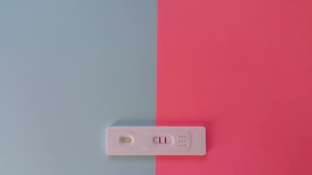 Hcg测试的背景是蓝色和粉色 显示了两条红线 上面画有问号的心形贴纸 怀孕测试 一个积极的结果 男孩或女孩的概念 — 图库视频影像
