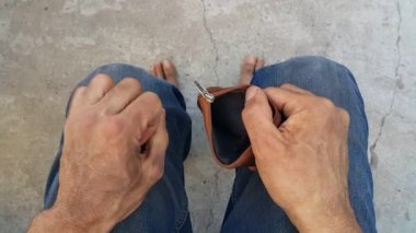 Kirli ellerle, evsiz fakir bir adam cüzdanının boş olduğunu fark eder. İşsiz bir adam. Şirketin iflası demek. Yoksulluk ve sefalet. İhtiyacı olan vatandaşlar. Açlık ve soğuk. Odaklanmadan çıplak ayaklar.
