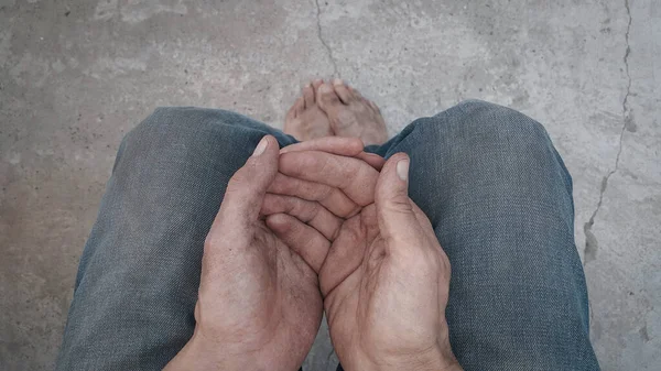 Begging. Outstretched hands. Barefoot. A homeless person. Diminution of money. Poor man. A beggar in the transition. An unemployed citizen. There is no work. Dirty hands and feet. Stink and dirt.