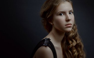 Uzun dalgalı saçlı güzel bir kızın klasik stüdyo portresi.