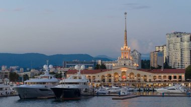Kuleleri ve yatları olan bir bina. Akşam Soçi 'de (Rusya) batan güneşin altında liman)