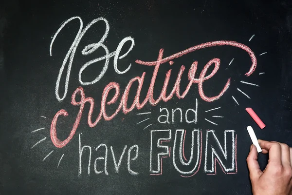 Цитата - Be creative and have fun- on black chalkboard handwritten by color chalks with hand Стоковое Изображение