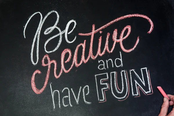 Цитата - Be creative and have fun- on black chalkboard handwritten by color chalks with hand Стоковое Фото