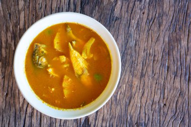 Ananas balıklı ekşi çorba, Tamarind aromalı levrek, ananaslı Güney Tayland Çorbası, Tayland yemeği ve beyaz kase ahşap arka planda sebze.