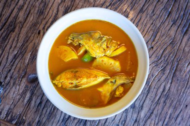 Ananas balıklı ekşi çorba, Tamarind aromalı levrek, ananaslı Güney Tayland Çorbası, Tayland yemeği ve beyaz kase ahşap arka planda sebze.