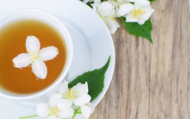 Ahşap arka planda yasemin çiçekli bir fincan çay.