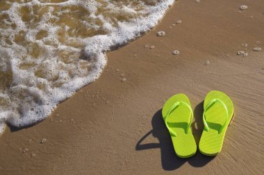 Sahilde parmak arası terlikler, deniz dalgaları.