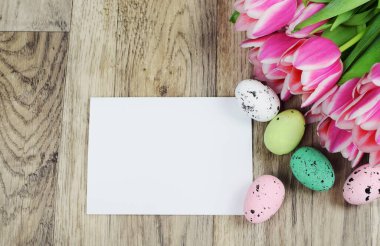 Ahşap zemin üzerinde paskalya yumurtaları ve laleler