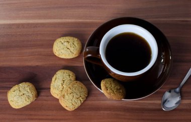 Tahta bir masada bir fincan kahve ve kurabiye.