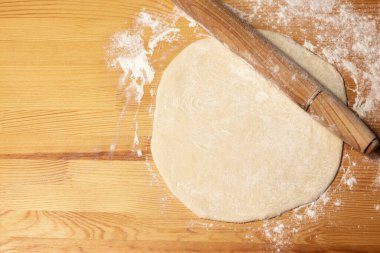 Tahta arka planda pizza hamuru. Merdane ve un. Seçici odak, üst görünüm.