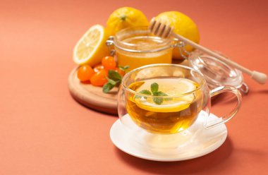 Naneli ve limonlu zencefilli çay. Sağlıklı ve sıcak bir içecek. Bal kavanozunda sıvı bal. Parlak arka planda kristal bardak. Seçici odak.