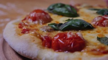 Domatesli, kirazlı, peynirli ve fesleğenli ev yapımı pizza. Geleneksel İtalyan yemeği. Tahta üzerinde pizza. Yakın çekim videosu