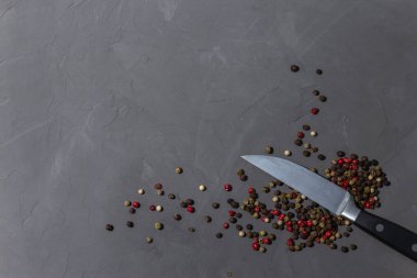 Bıçakla biber karışımı. Siyah, kırmızı ve beyaz biberler siyah taş arka planda izole edilmiş. Yakın çekim, üst görünüm, boşluğu kopyala