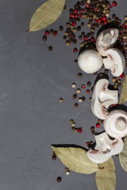 Siyah taş arka planda mantar ve baharatlar. Siyah, kırmızı, beyaz biber, defne yaprağı ve karanfil. Dilimlenmiş mantar. Kopyalama alanı, üst görünüm, yakın çekim fotoğraf. 